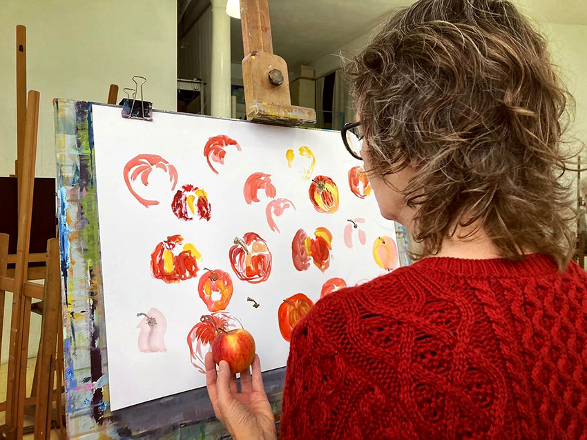 Lucy seen from behind while painting an apple